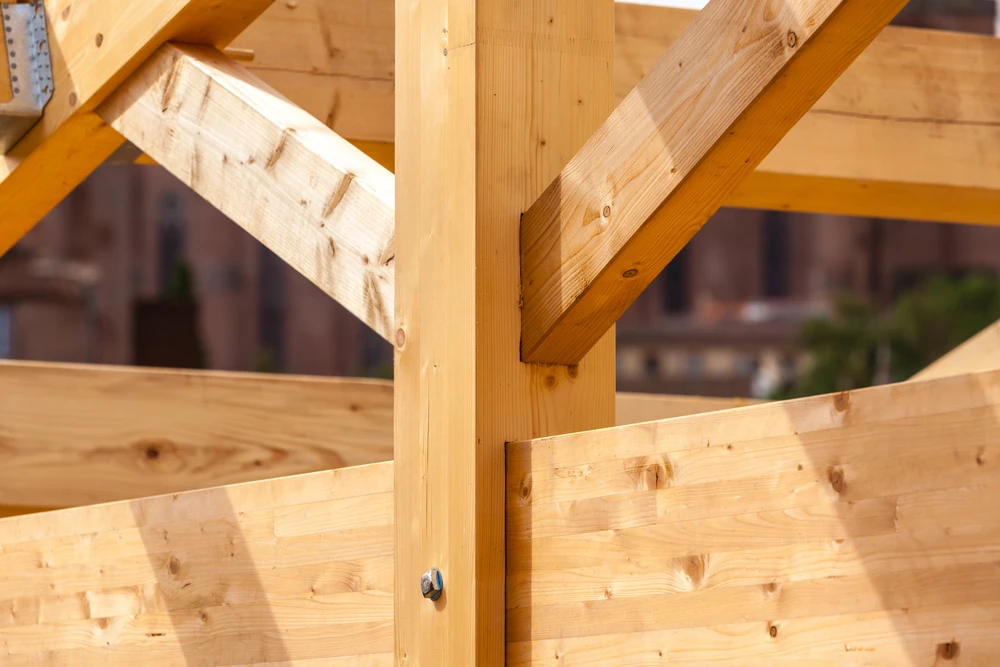 Chantier de couverture en extérieur avec deux couvreurs installant des tuiles métalliques grises sur charpente bois